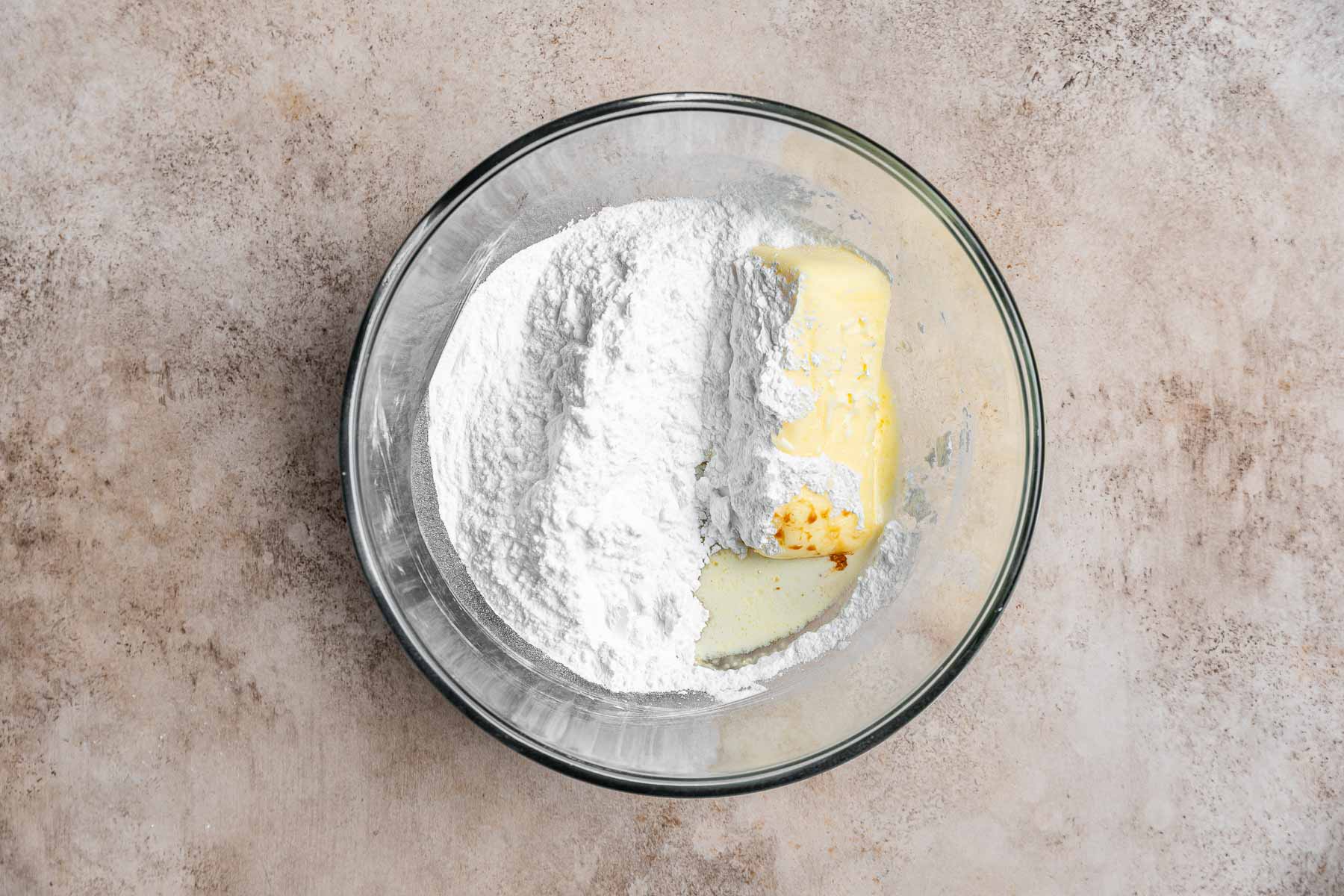 Butter, powdered sugar and cream in clear bowl.