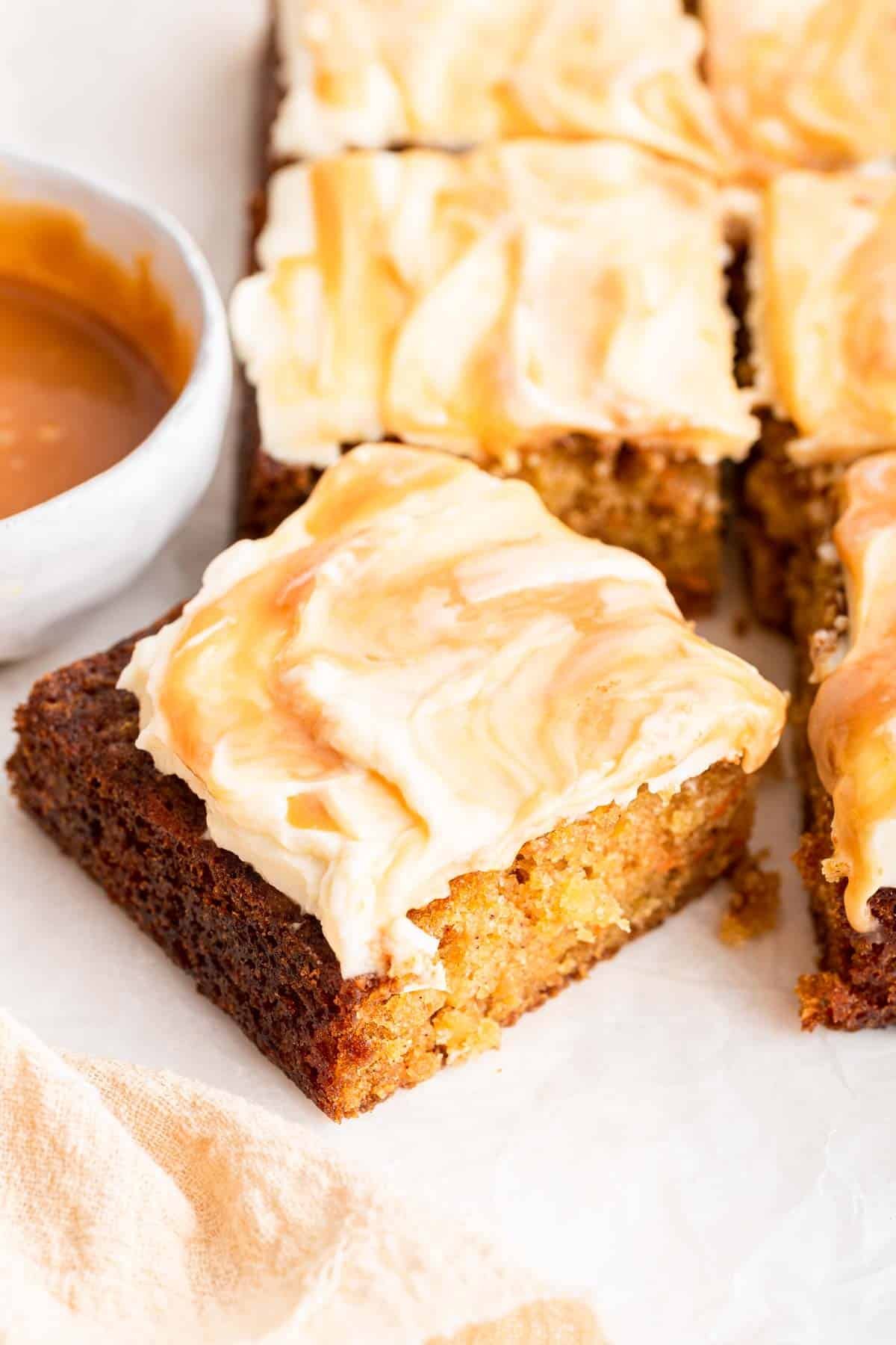 One square piece of carrot cake with caramel swirled frosting.