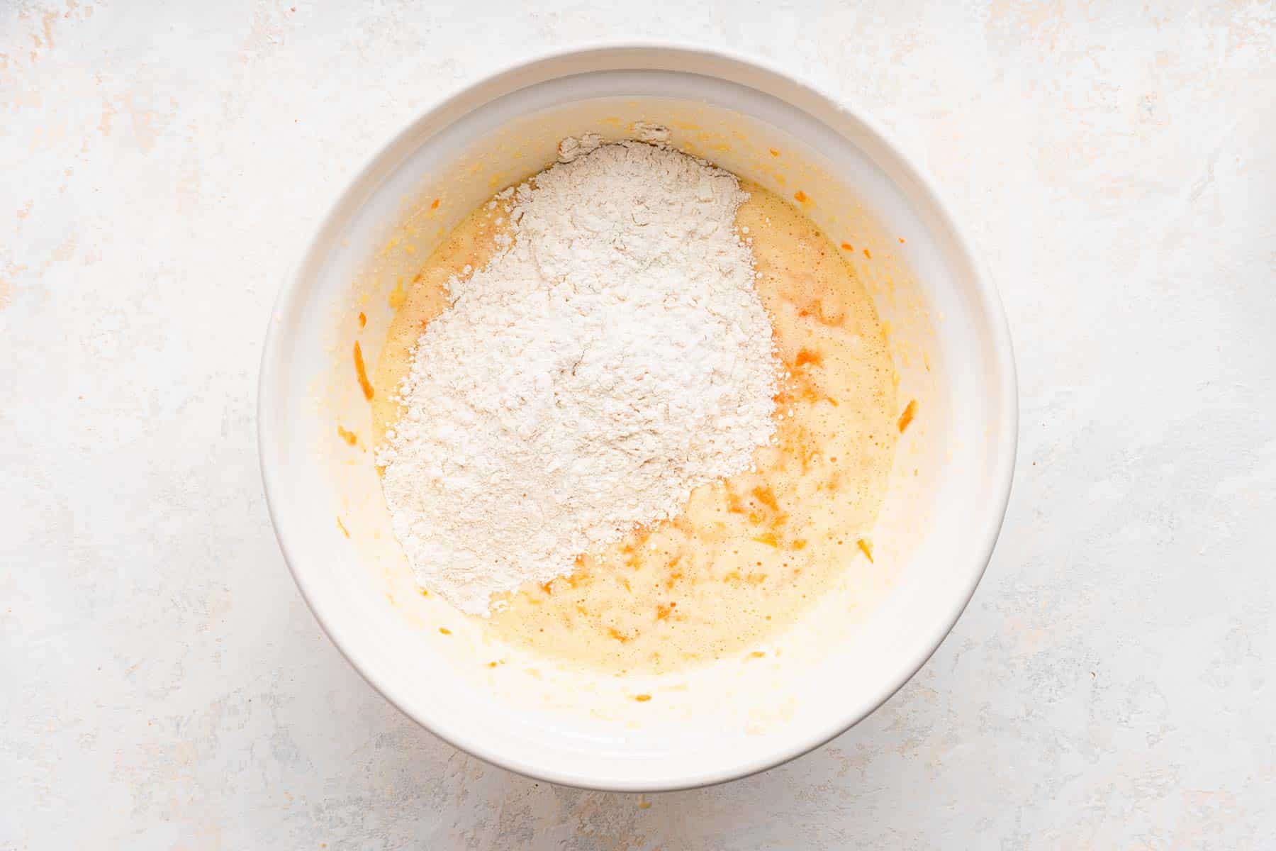 Dry ingredients over wet ingredients in a white bowl.