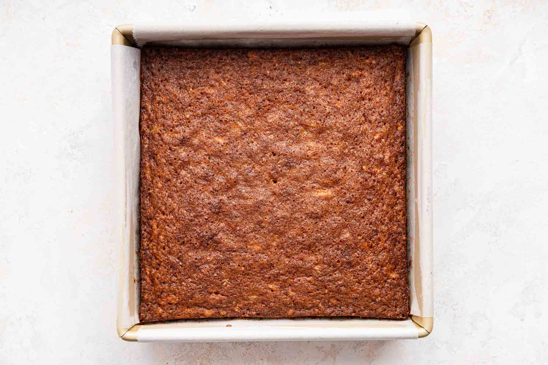 Square pan with brown cake inside.