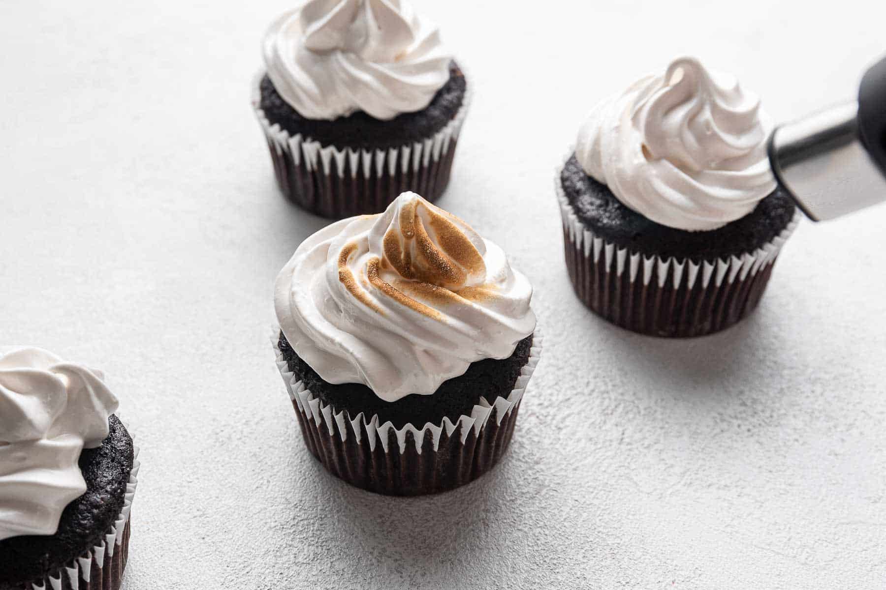 Torching marshmallow frosting on a chocolate cupcake.