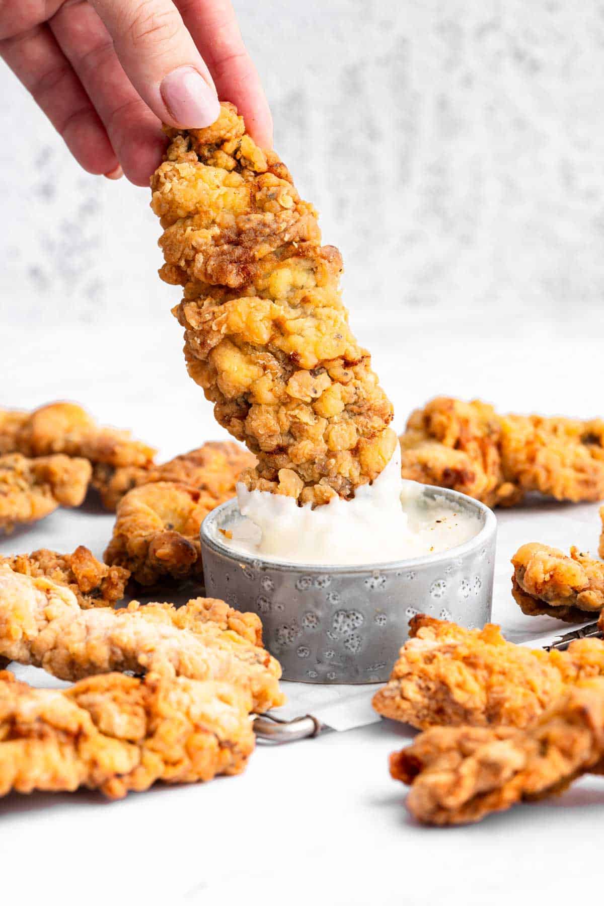 Hand dipping a steak finger in sauce.