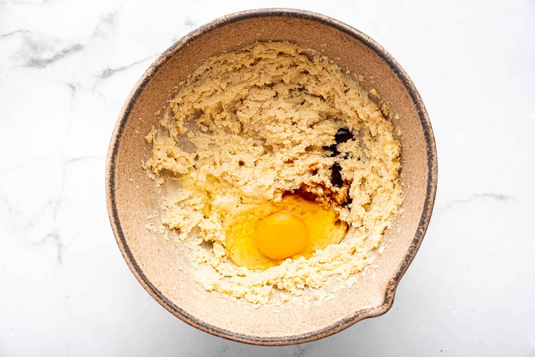 Brown bowl with creamed butter, sugar, egg and vanilla.