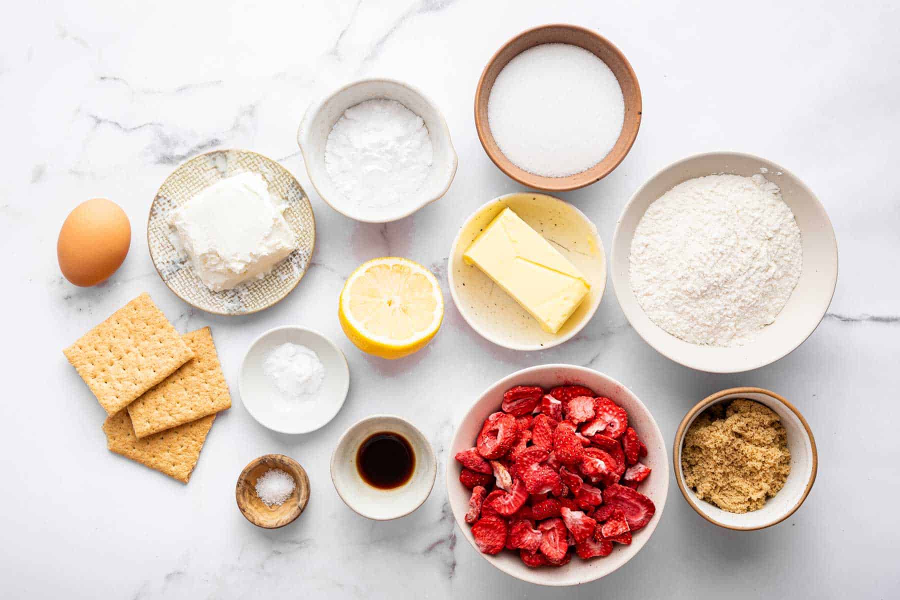Lots of small white bowls with graham crackers, sugars, butter, and vanilla inside.