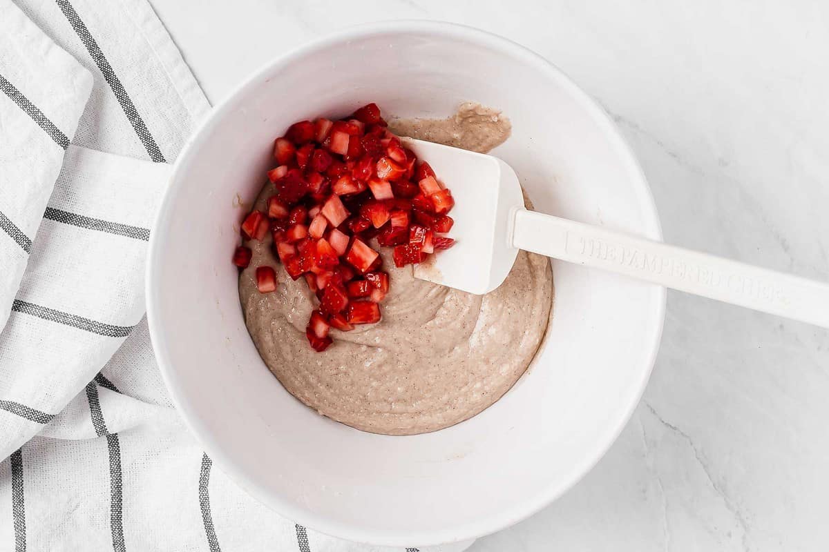 Fresh chopped strawberries in white muffin batter.