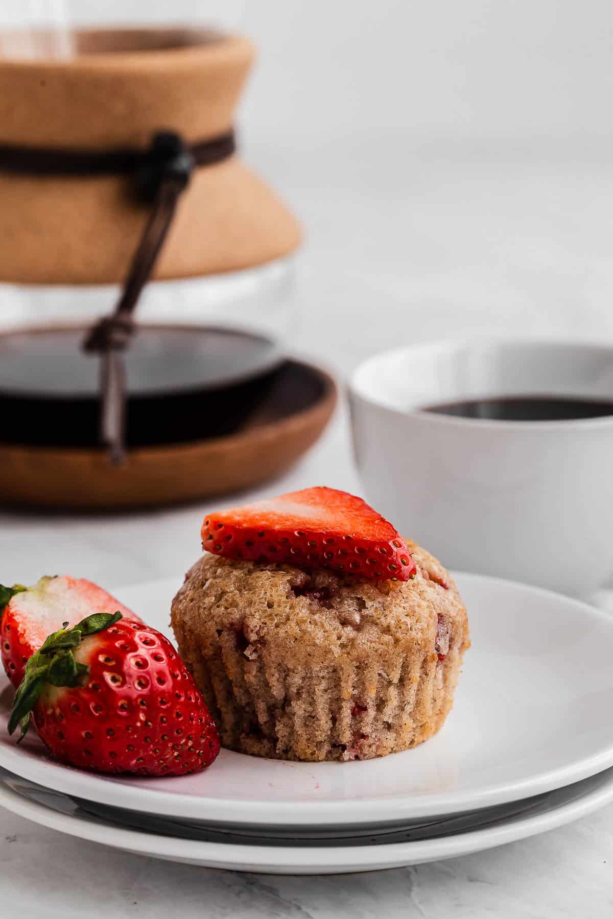 Strawberry muffin on a plate with coffee cup.