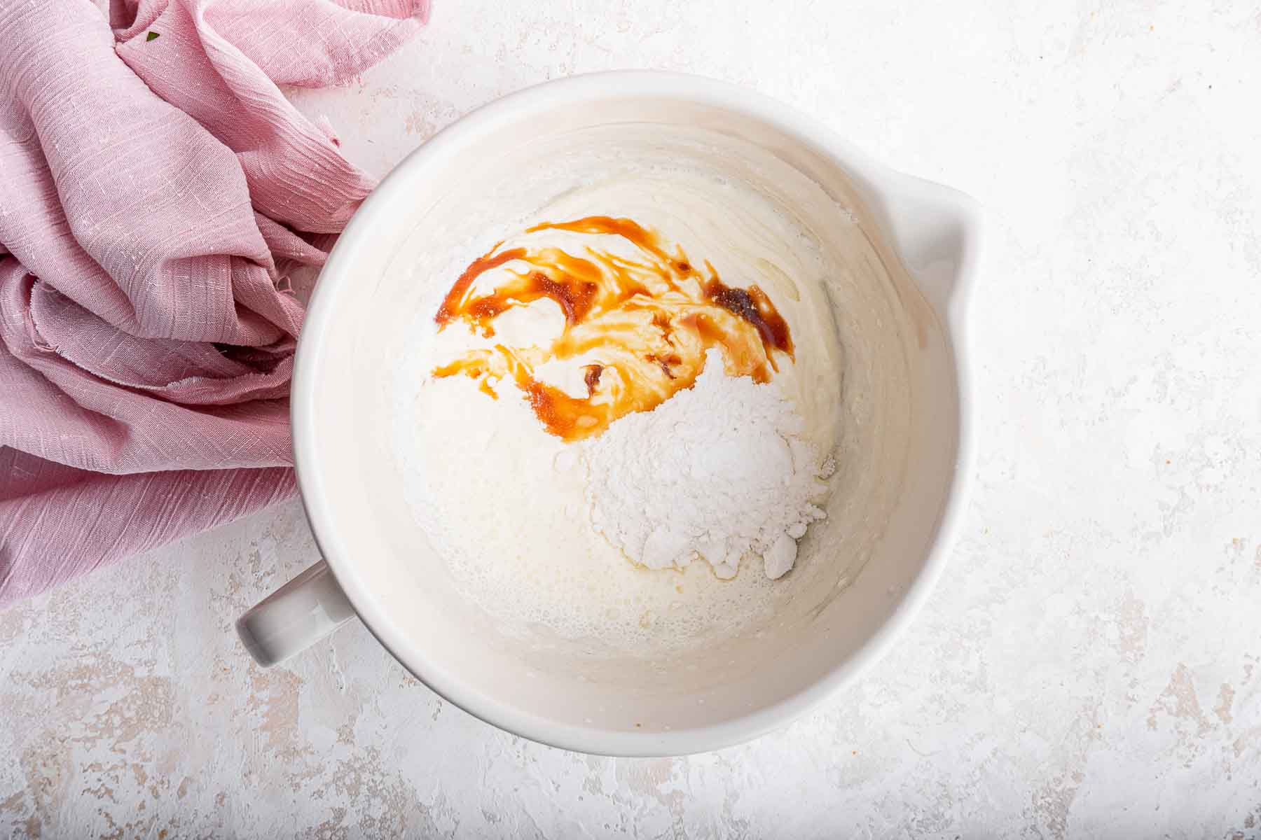 Bowl of whipped cream with vanilla splashed on top.