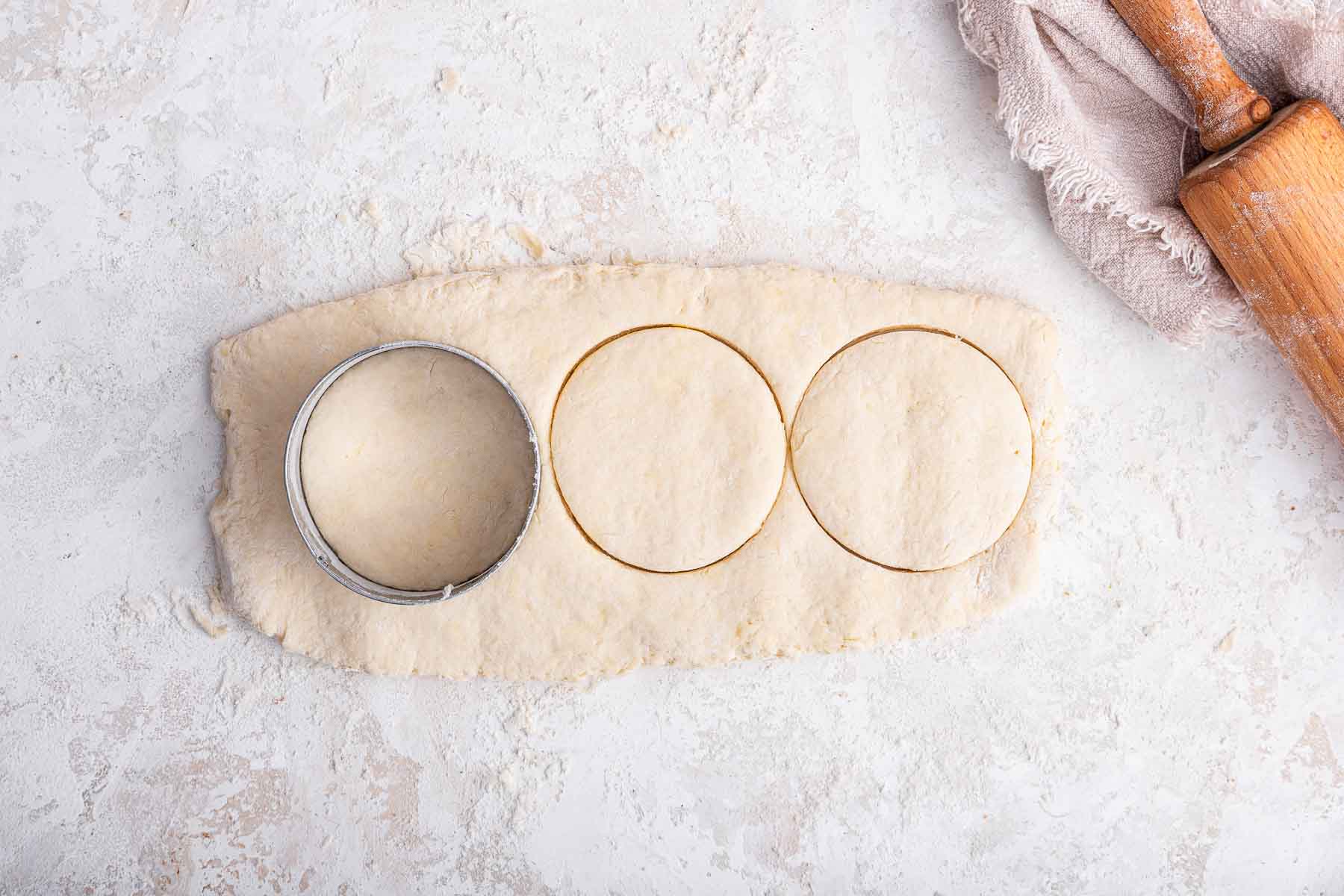 Biscuit cutter making three biscuits in raw dough.
