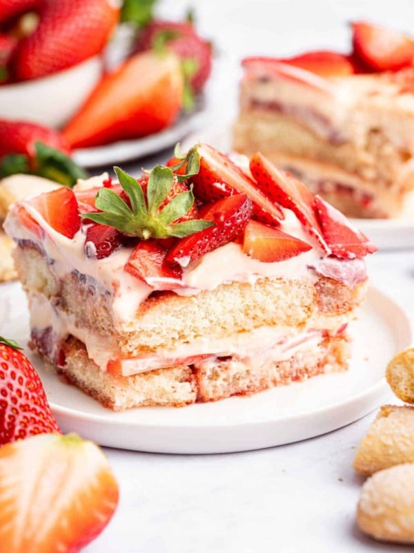 Square piece of strawberry tiramisu with fresh berries on top.