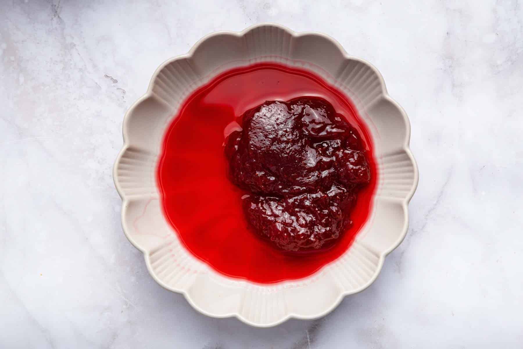 Shallow bowl with red liquid and pile of red jam.