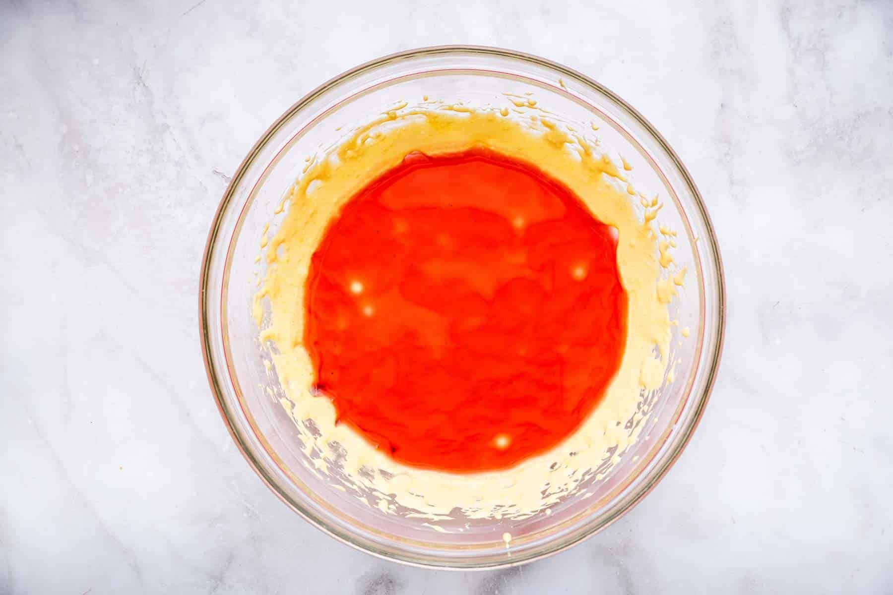 Yellow mixture with red liquid being folded in.