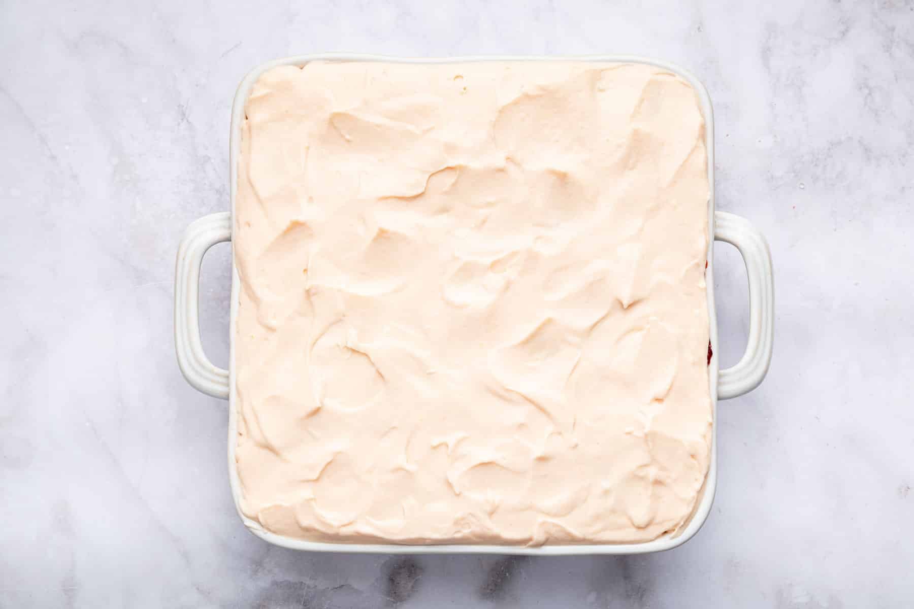 Square dessert piled high with whipped heavy cream.