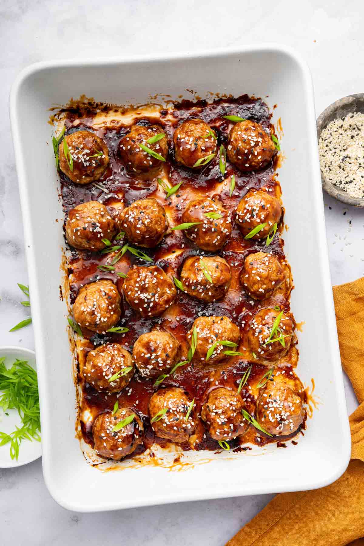 Cooked teriyaki chicken meatballs in white baking dish.