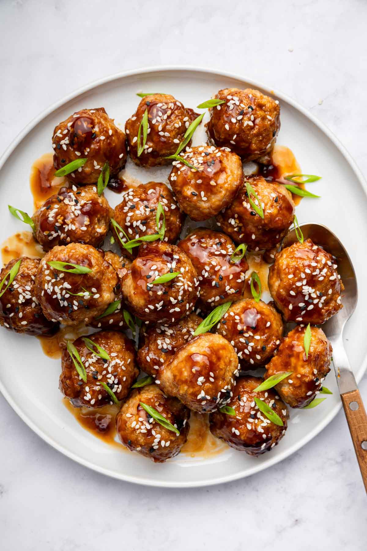 White plate with shiny glazed teriyaki meatballs on top.
