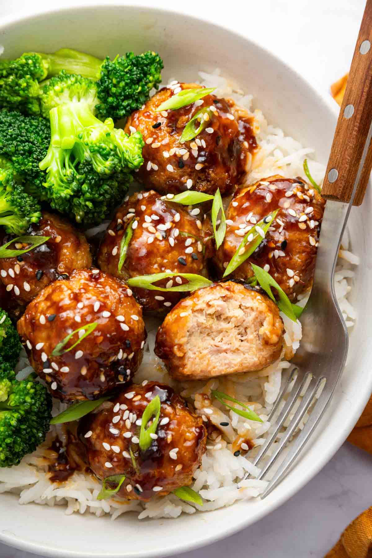 Bowl of teriyaki chicken meatballs over rice with broccoli on the side.