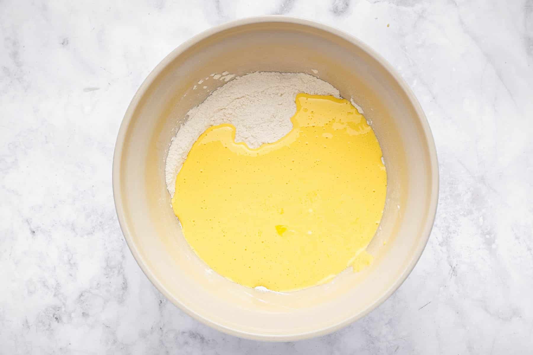 Bowl of yellow liquid with flour underneath.