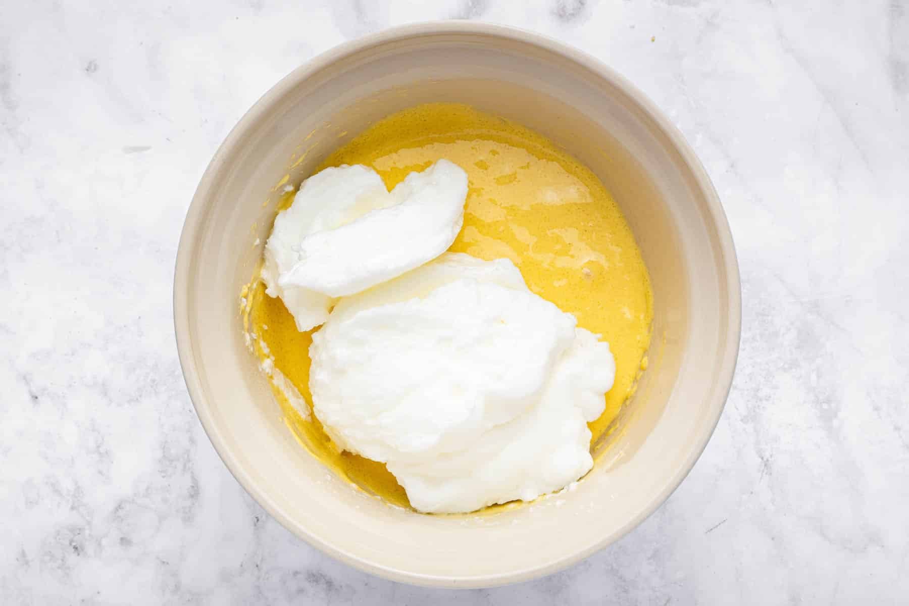 Stirring beaten egg whites into yellow sponge cake batter.