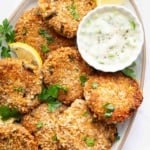 Vertical image of tuna patties on plate with bowl of ranch on the side.