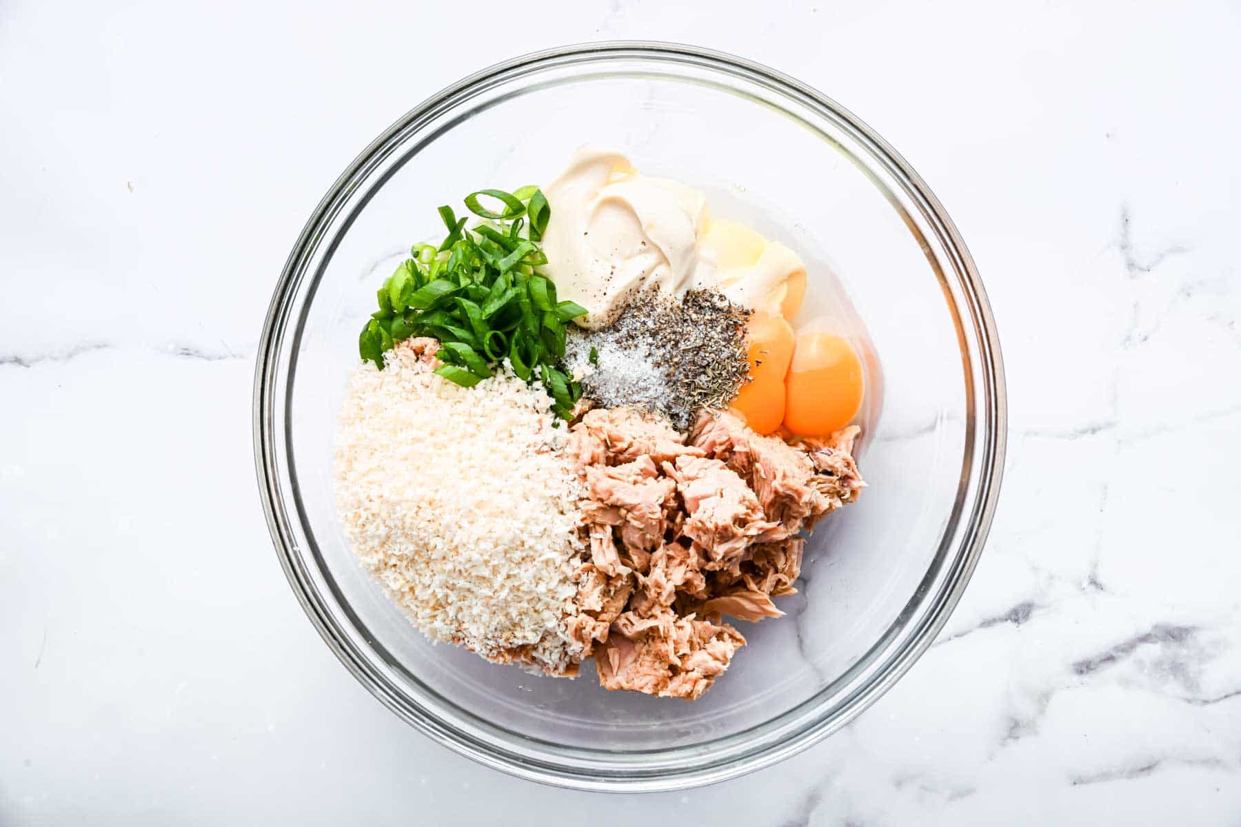 Clear bowl with vegetables, eggs and breadcrumbs.