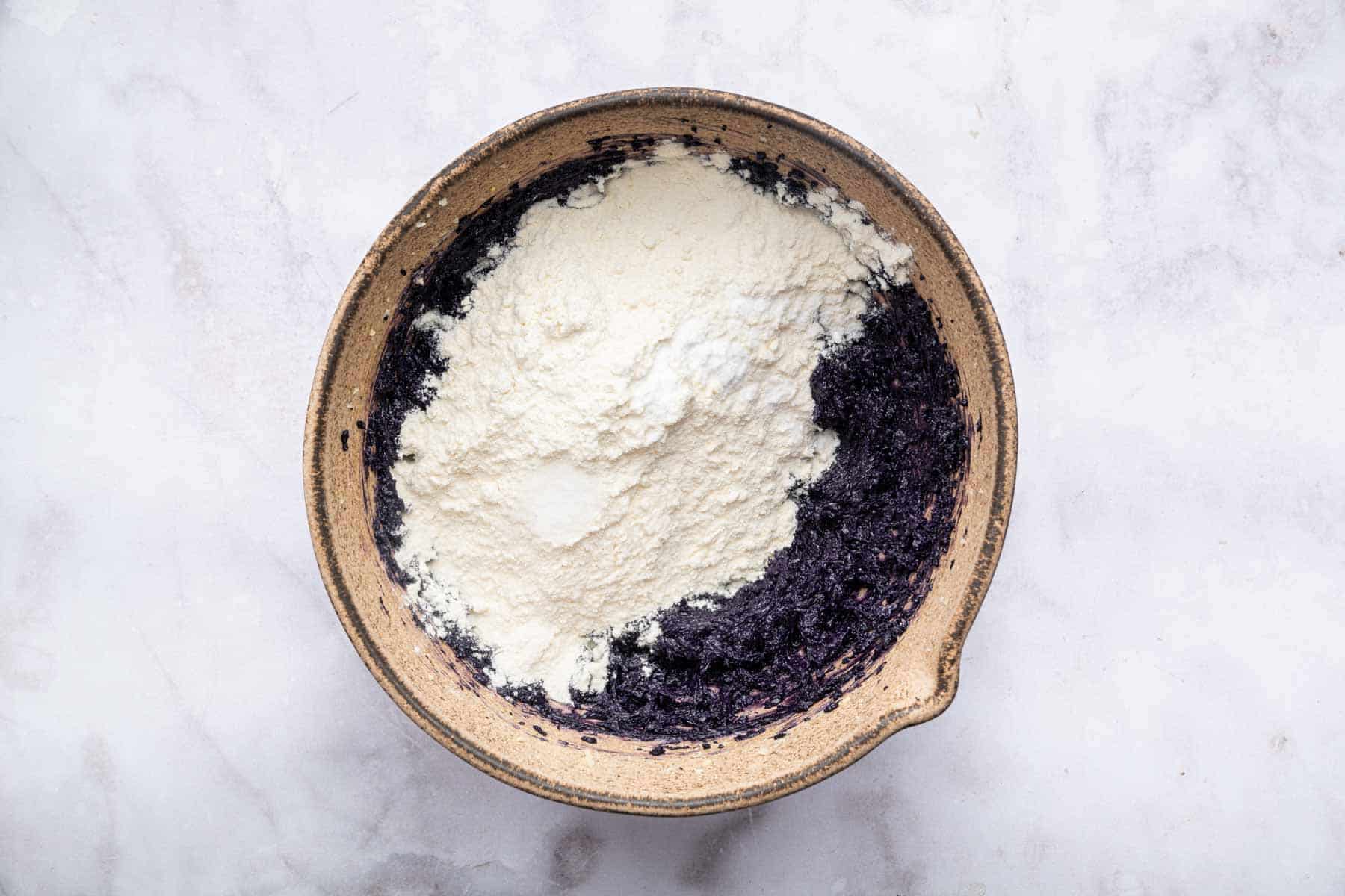 White flour sprinkled over purple dough.