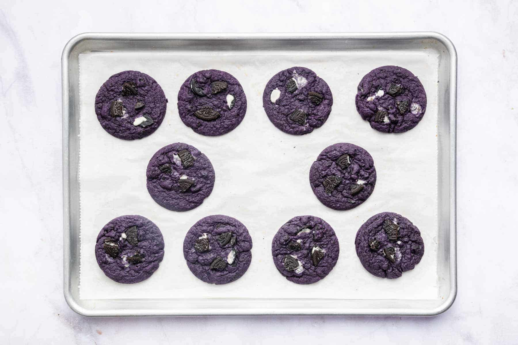 Sheet pan of ube cookies with crushed Oreos on top.