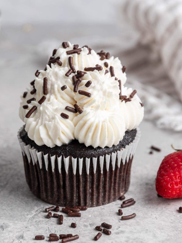 Chocolate cupcakes with white icing and chocolate sprinkles.