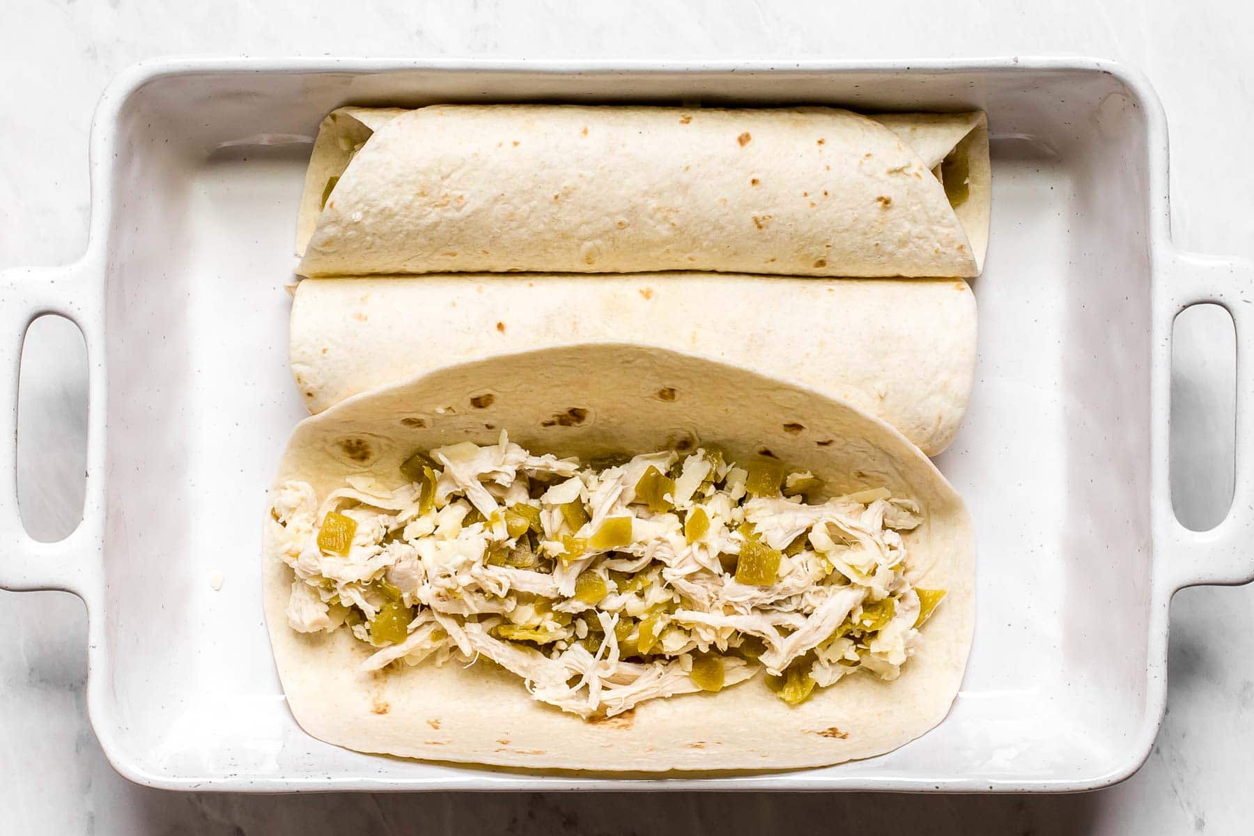 Rolling up a chicken tortilla with cheese.