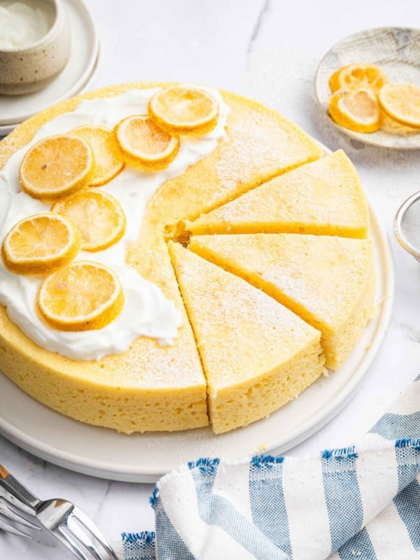 Round yellow yogurt cake recipe on plate with lemon slices on top.