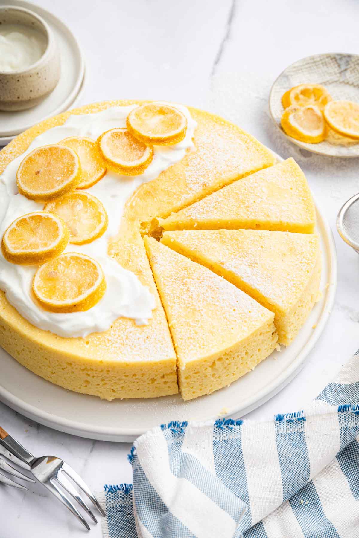 Round yellow yogurt cake recipe on plate with lemon slices on top.
